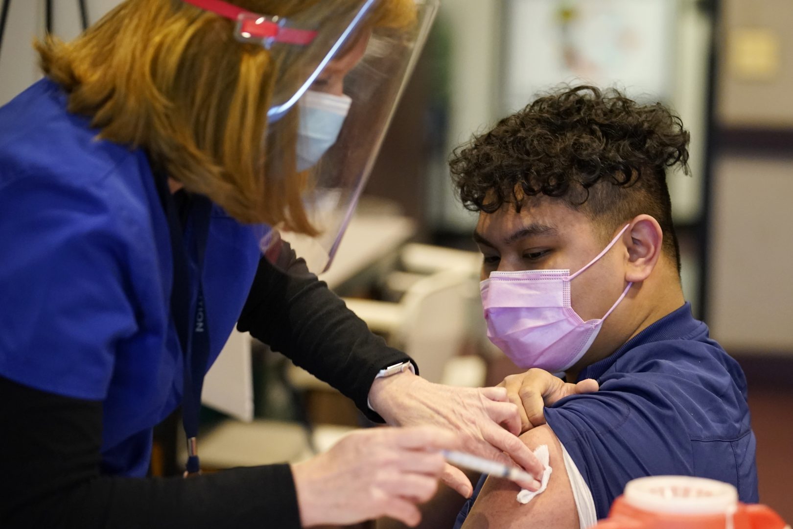 Penny Cracas, left, with the Chester County, Pa., Health Department, administers the Moderna COVID-19 vaccine to EMT Christian Ventura at the Chester County Government Services Center, Tuesday, Dec. 29, 2020, in West Chester, Pa. (AP Photo/Matt Slocum)