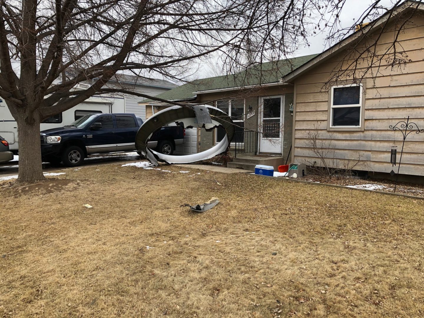 In this photo provided by the Broomfield Police Department on Twitter, debris is scattered in the front yard of a house at near 13th and Elmwood, Saturday, Feb. 20, 2021, in Broomfield, Colo. A commercial airliner dropped debris in Colorado neighborhoods during an emergency landing Saturday. The Broomfield Police Department said on Twitter that the plane landed safely at Denver International Airport and that no injuries had been reported from the incident.  (Broomfield Police Department via AP)