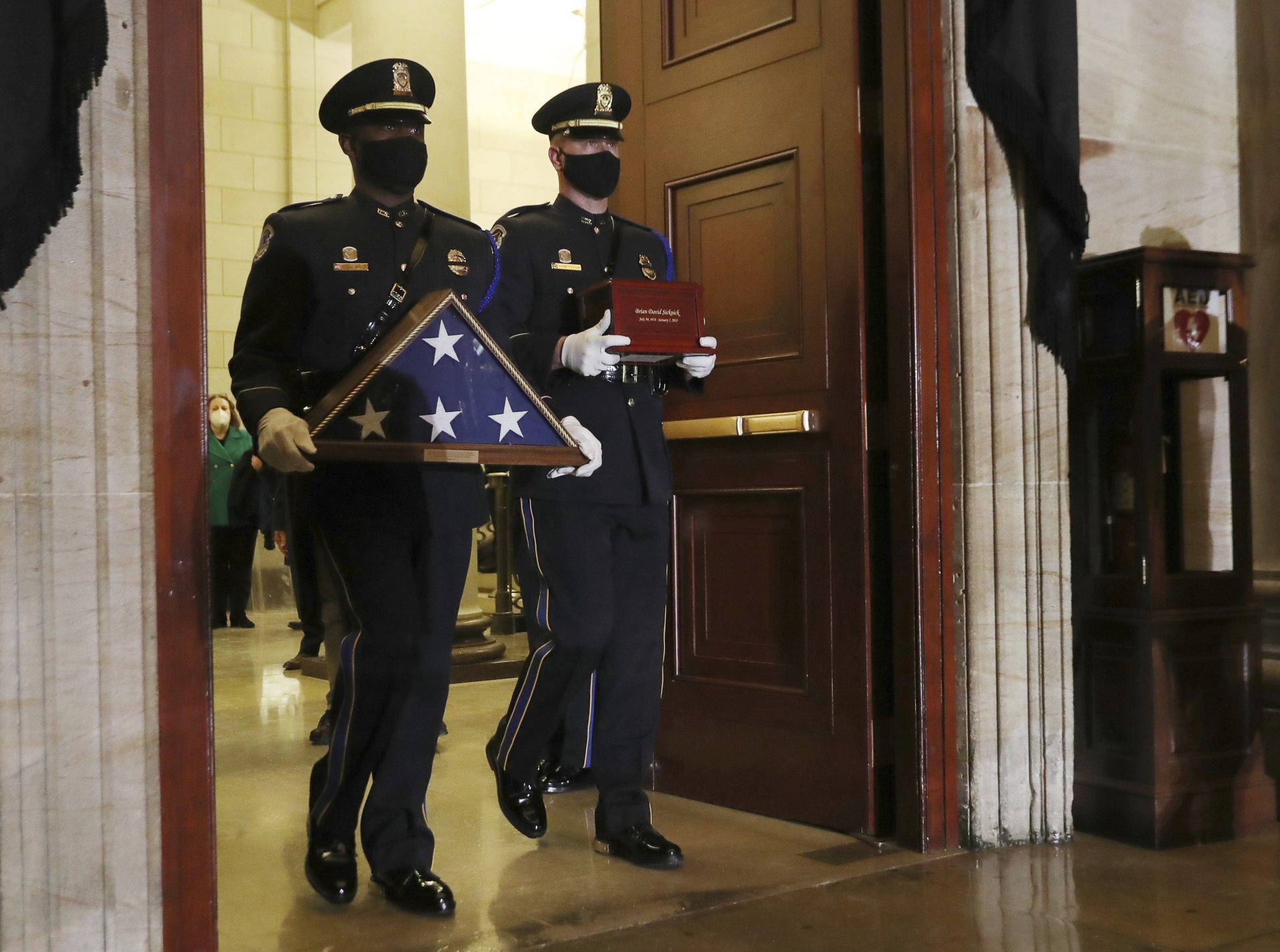 An honor guard carry an urn with the cremated remains of U.S. Capitol Police officer Brian Sicknick and a folded flag into the Capitol Rotunda to lie in honor Tuesday, Feb. 2, 2021, in Washington.