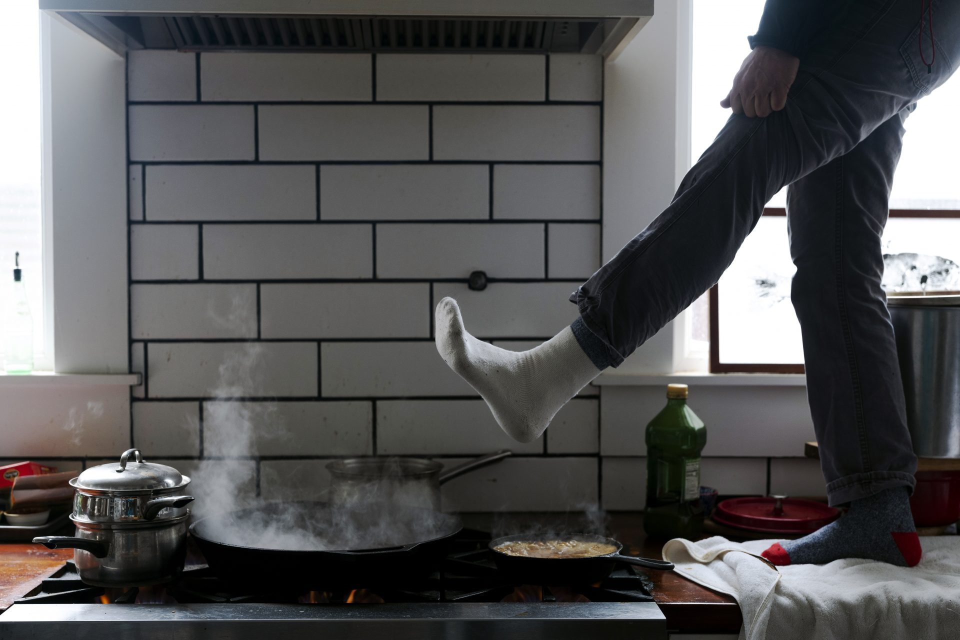 Jorge Sanhueza-Lyon stands on his kitchen counter to warm his feet over his gas stove Tuesday, Feb. 16, 2021, in Austin, Texas. Power was out for thousands of central Texas residents after temperatures dropped into the single digits when a snow storm hit the area on Sunday night.