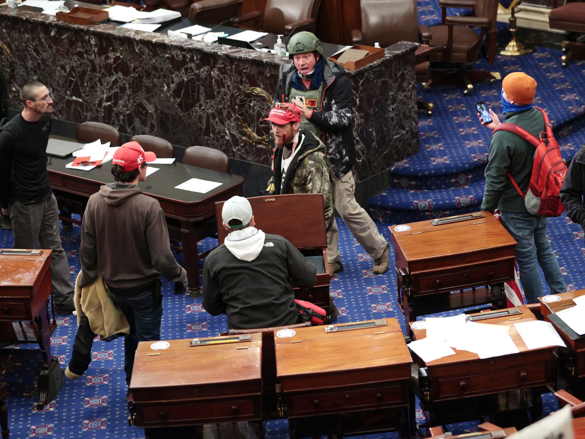 Bruno Cua is allegedly seen here with his back to the camera, holding a tan jacket. Prosecutors say he entered the Senate chamber of the U.S. Capitol on Jan. 6 with a handful of other rioters.