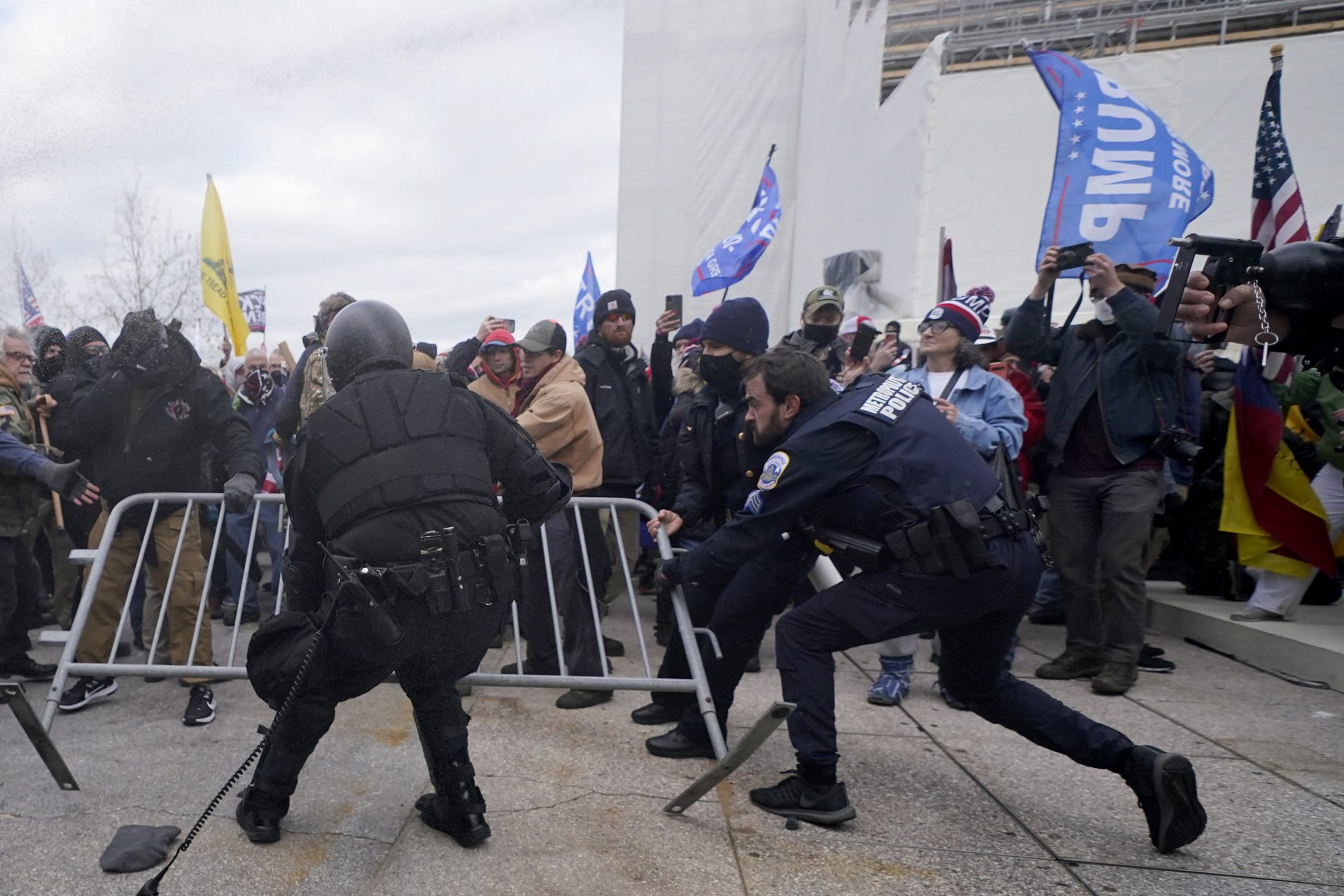 Police try to retrieve a barricade during a scuffle with President Donald Trump supporters at the U.S. Capitol, Wednesday, Jan. 6, 2021, in Washington.