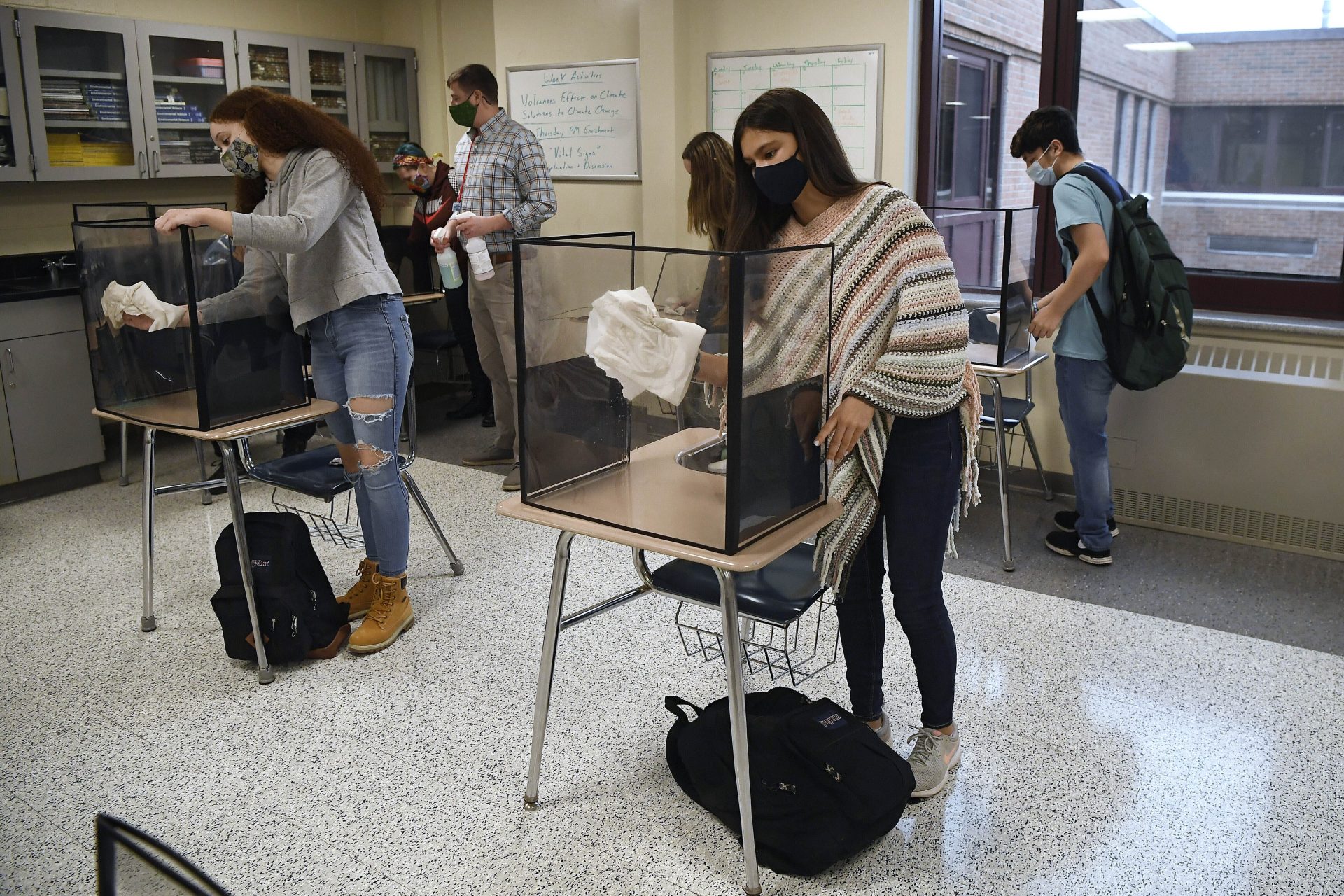 In this March 18, 2021, file photo, students in teacher Christopher Duggan's science class clean their work areas at the end of class at Windsor Locks High School in Windsor Locks, Conn.