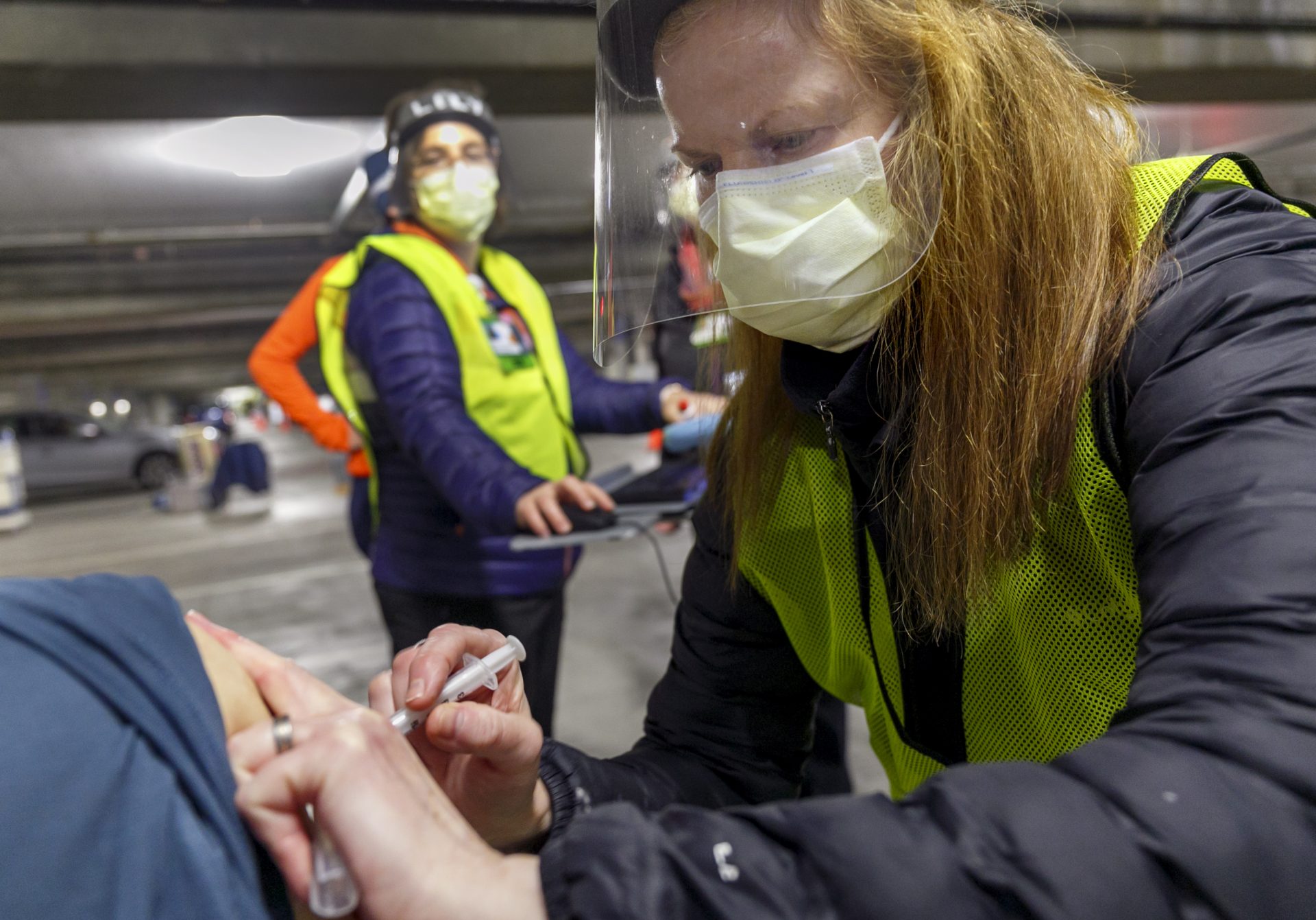 In this Jan. 10, 2021, file photo, pharmacist Colleen Naughtin, right, administers the Moderna COVID-19 vaccine at a drive-thru vaccination clinic in Portland, Ore.