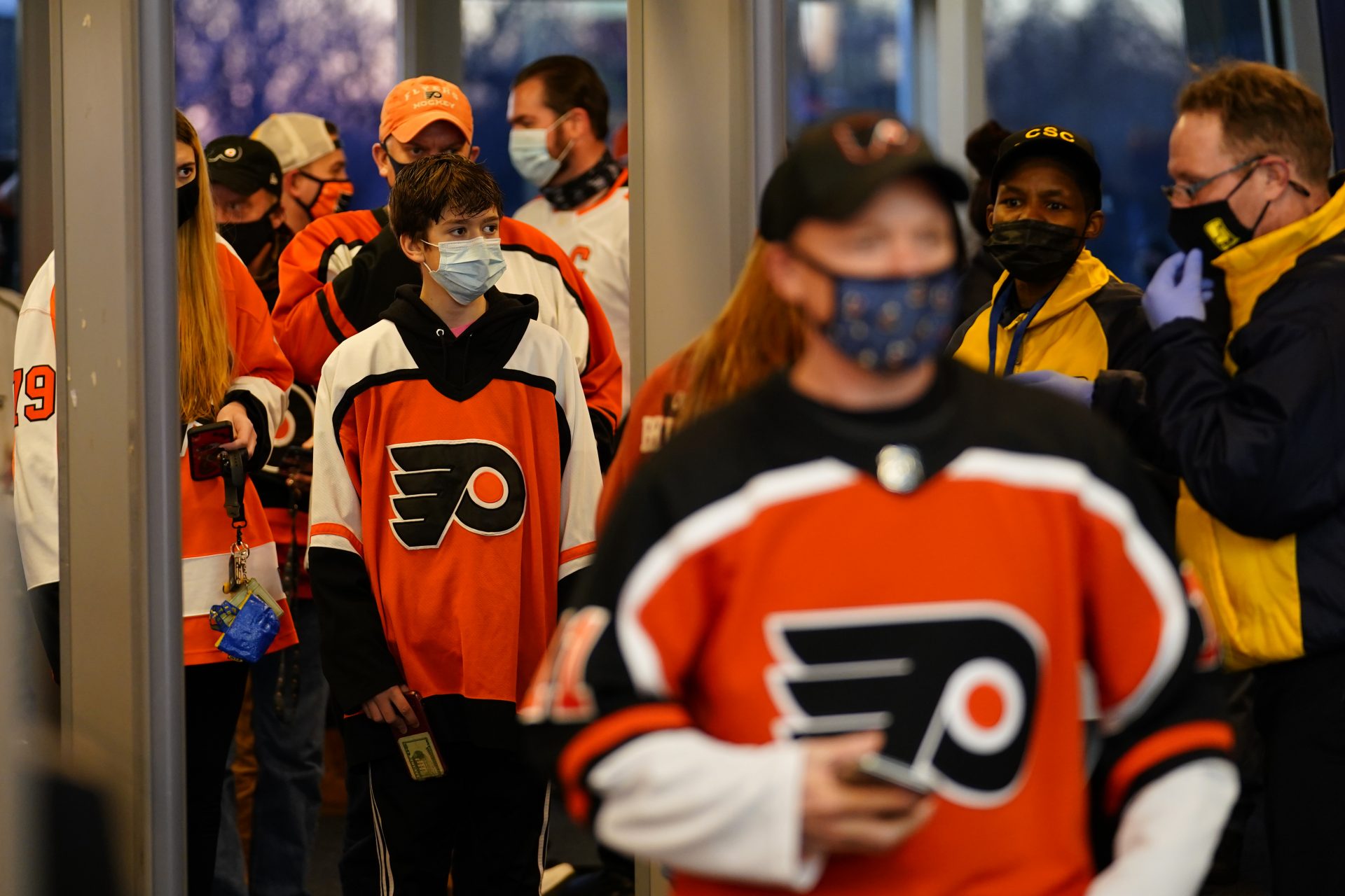 Fans walk through security at the Wells Fargo Center before an NHL hockey game between the Philadelphia Flyers and the Washington Capitals, Sunday, March 7, 2021, in Philadelphia.