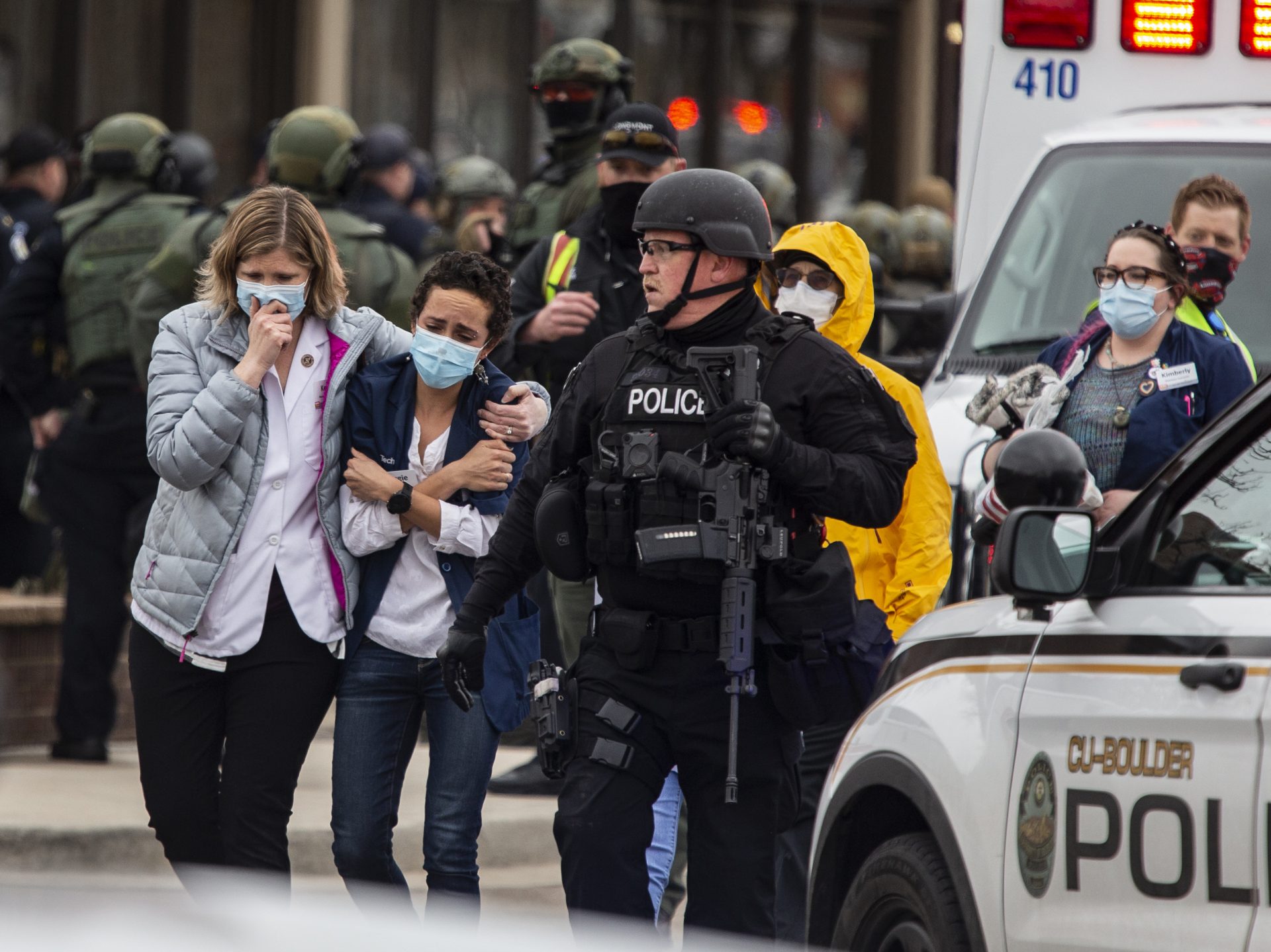 Health care workers walk out of a King Soopers grocery store after a gunman opened fire Monday in Boulder, Colo.