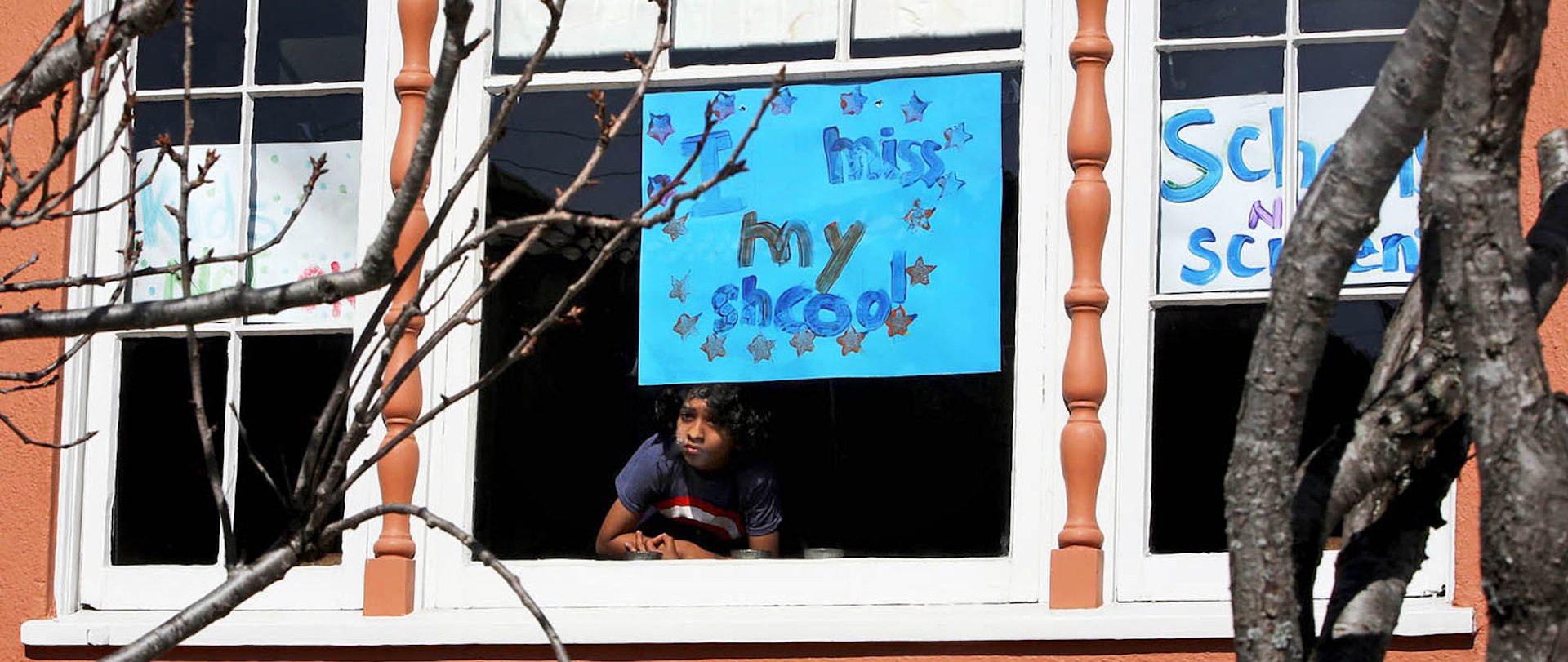 Jeevan Guha, 6, poses for a portrait near his homemade sign in San Francisco. His sign reads, "I miss my school."
