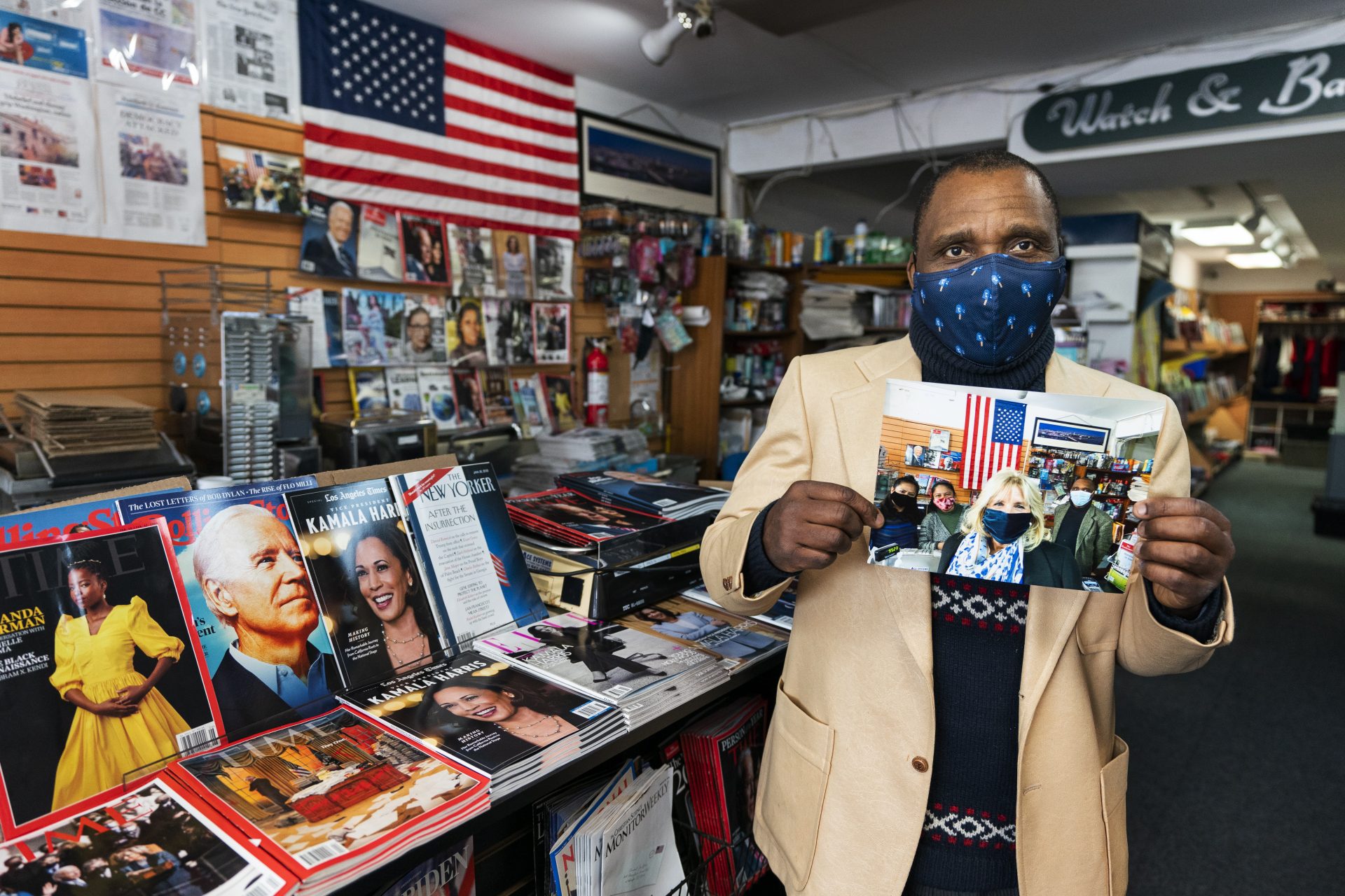 In this Feb. 19, 2021, photo store owner Stephen Bota pose for a picture with a picture him and wife and his wife's sister and first lady Jill Biden in Newsroom newsstand in Washington. (