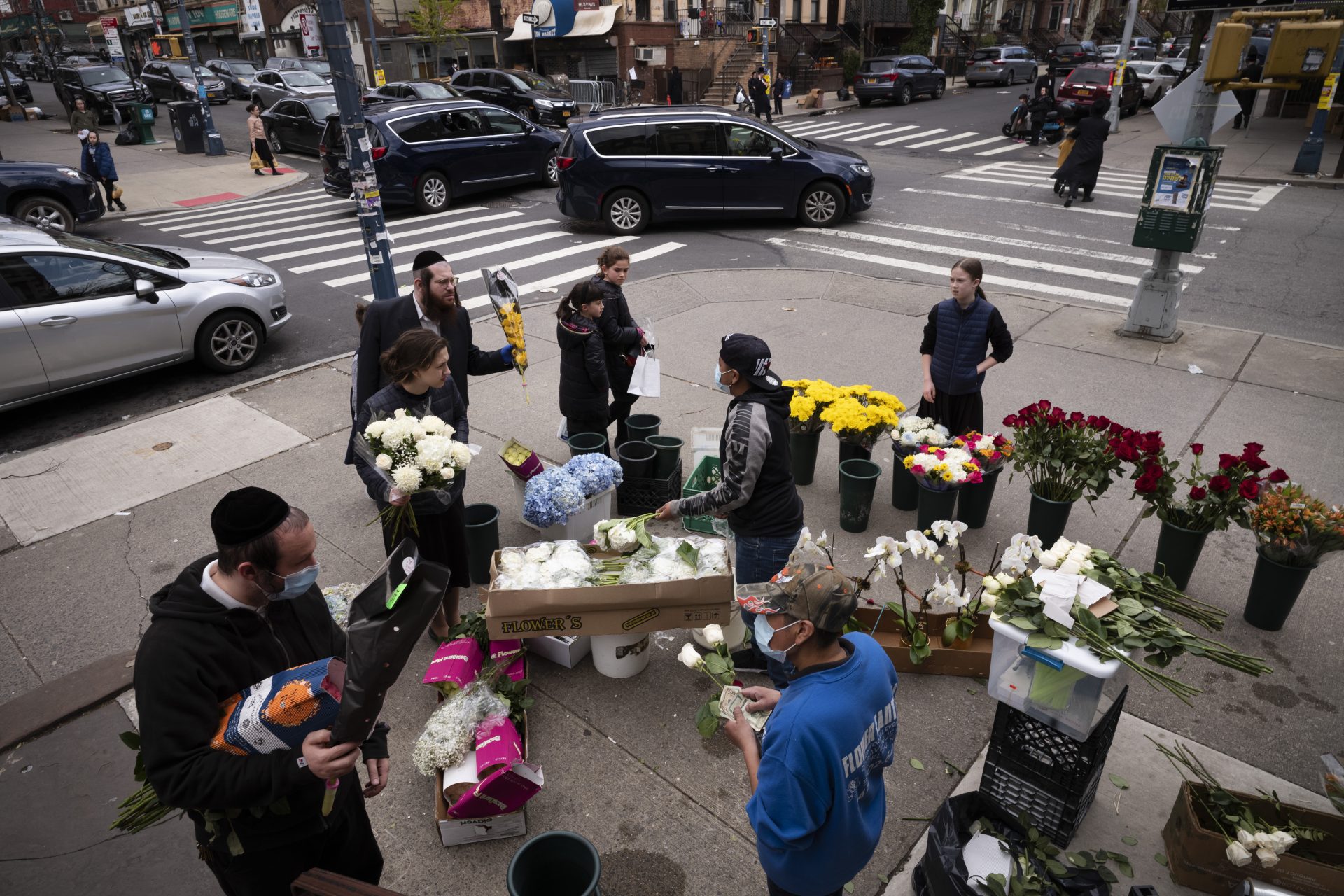 In this Wednesday, April 8, 2020 file photo, people buy flowers from a sidewalk flower stand on the first day of Passover in the Williamsburg neighborhood of New York during the coronavirus pandemic.