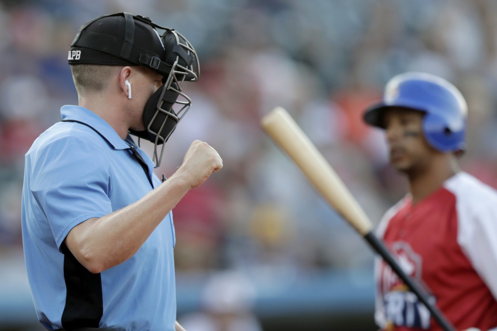 Home plate umpire Brian deBrauwere, left, calls a strike given to him by a radar system over an earpiece as Liberty Division's Tyler Ladendorf, right, of the High Point Rockers, strikes out to Freedom Division's Mitch Atkins, of the York Revolution, during the first inning of the Atlantic League All-Star minor league baseball game, Wednesday, July 10, 2019, in York, Pa. deBrauwere wore the earpiece connected to an iPhone in his ball bag which relayed ball and strike calls upon receiving it from a TrackMan computer system that uses Doppler radar. The independent Atlantic League became the first American professional baseball league to let the computer call balls and strikes during the all star game. 