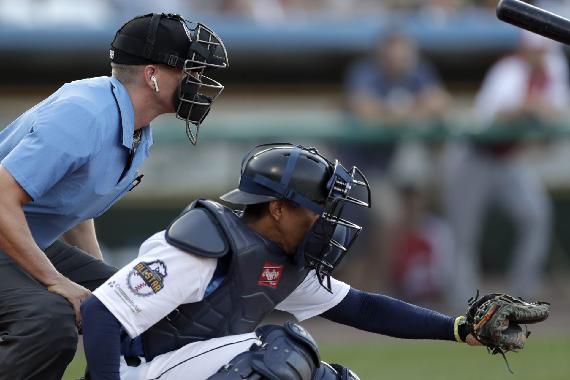 Home plate umpire Brian deBrauwere, left, huddles behind Freedom Division catcher James Skelton, of the York Revolution, as the official wears an earpiece during the first inning of the Atlantic League All-Star minor league baseball game, Wednesday, July 10, 2019, in York, Pa.