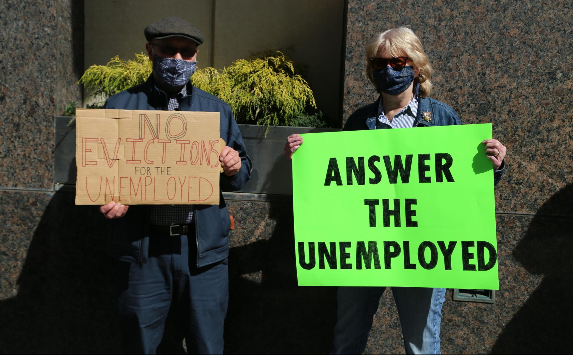 Two people hold signs at a rally in support of unemployed people in downtown Pittsburgh on Wednesday, March 10, 2021.