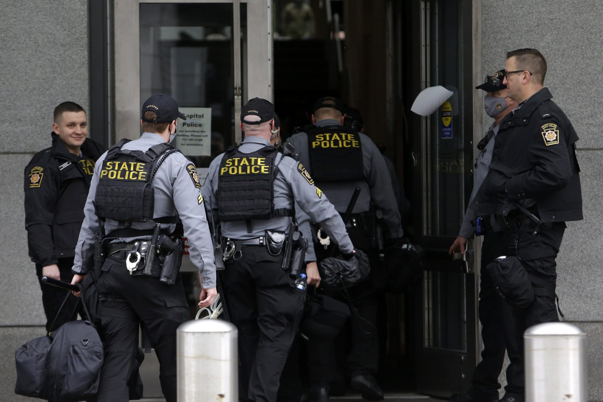 Pennsylvania State Police assemble and walk into a building near the Pennsylvania state capitol Sunday Jan. 17, 2021, in Harrisburg, Pa.