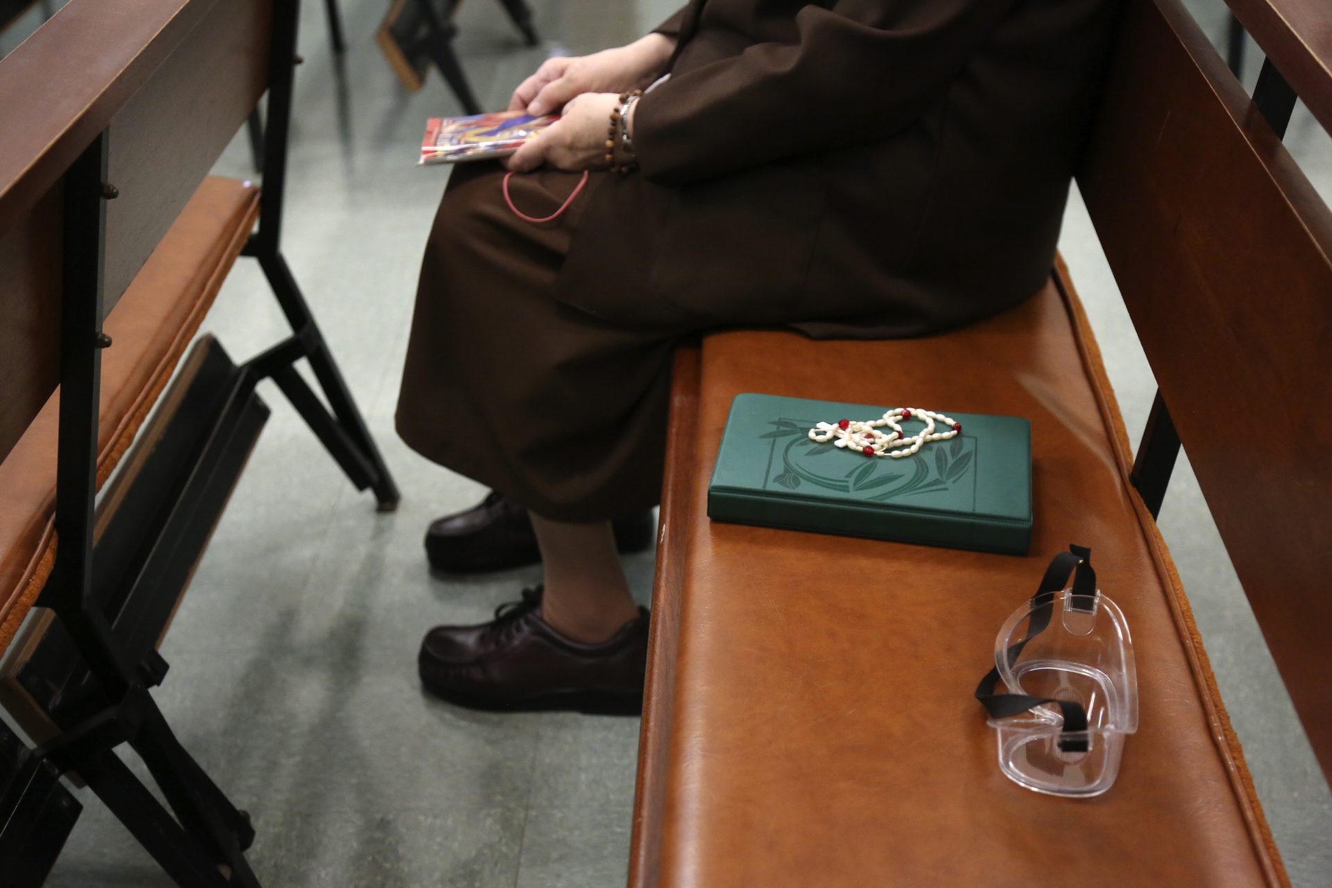 Sister Mary Carol Kardell, of the Felician Sisters of North America, sits beside a Bible, rosary beads and goggles during morning Mass at St. Anne Home in Greensburg, Pa., on Thursday, March 25, 2021. Last October the nuns lost one of their own, Sister Mary Evelyn Labik, to the coronavirus.