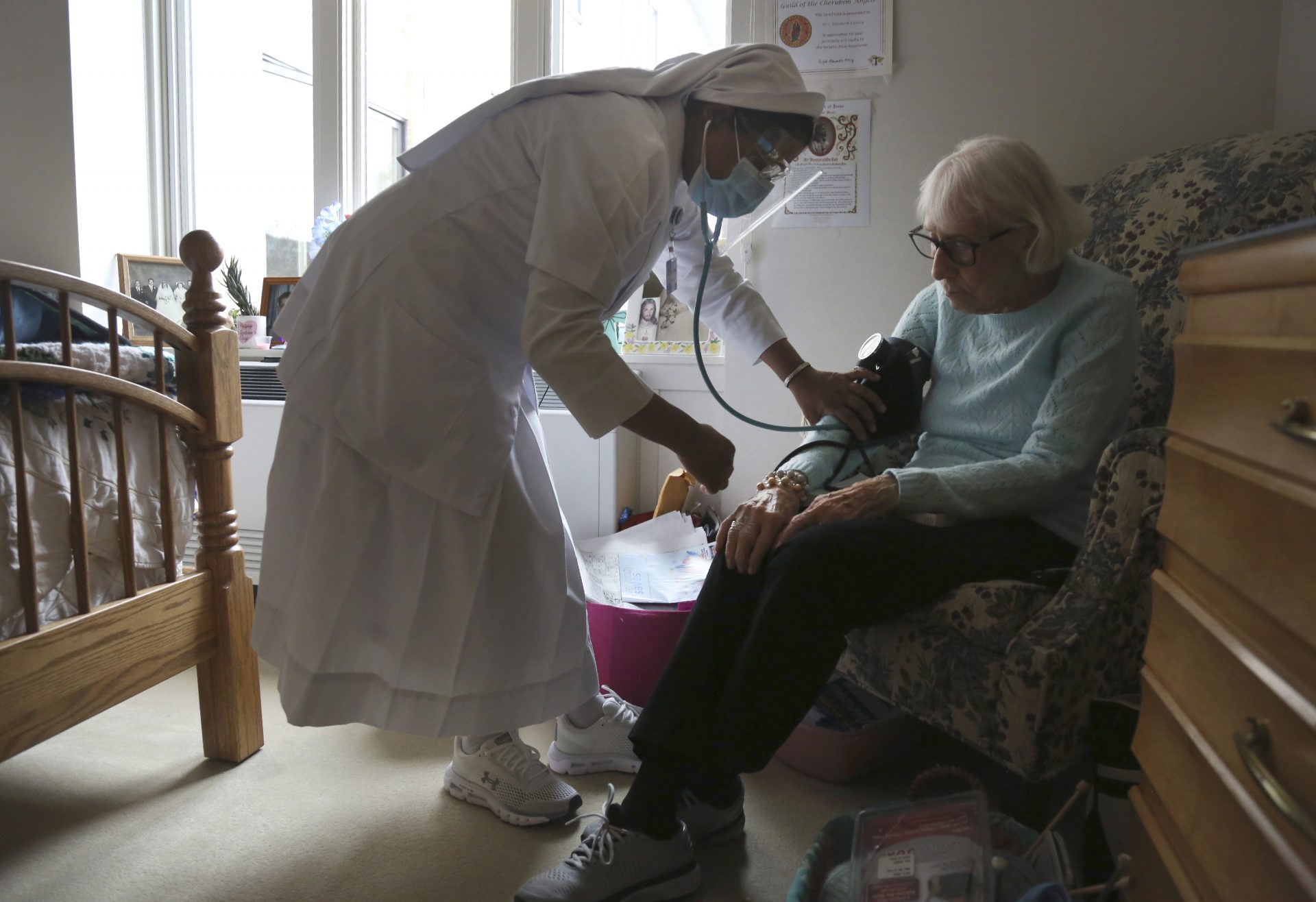 Sister Rose Nellivila checks the blood pressure of Lorraine Catney, a resident of Villa Angela at St. Anne Home nursing facility in Greensburg, Pa., Thursday, March 25, 2021.