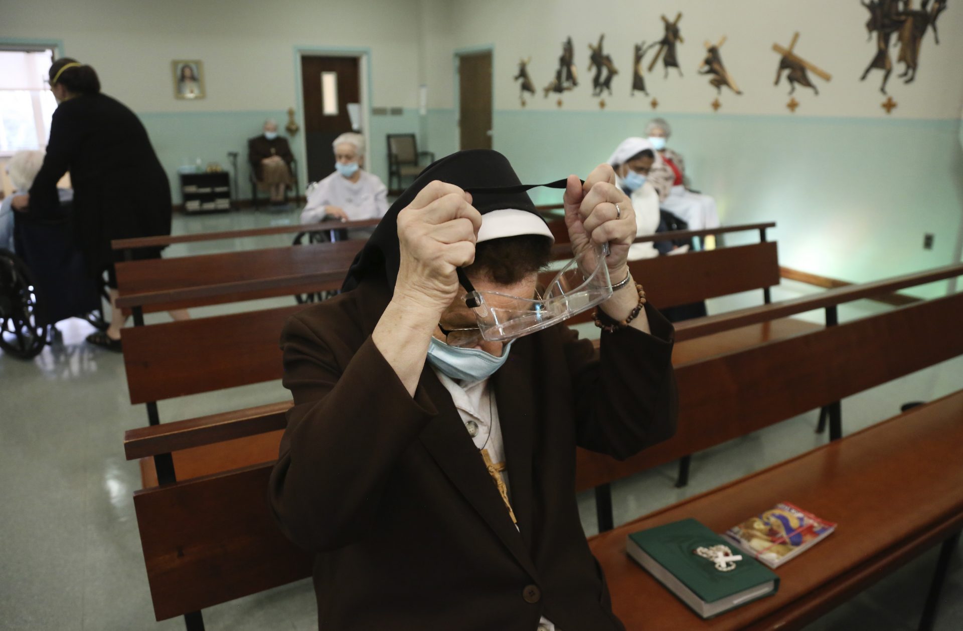 Sister Mary Carol Kardell, of the Felician Sisters of North America, puts on goggles after morning Mass at St. Anne Home in Greensburg, Pa., on Thursday, March 25, 2021.