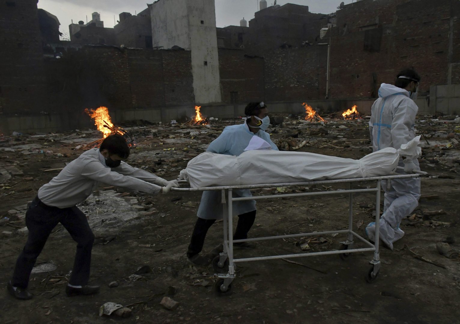 In this May 6, 2021, photo, the body of a COVID-19 victim is wheeled in for cremation in a ground that has been converted into a crematorium in New Delhi, India.