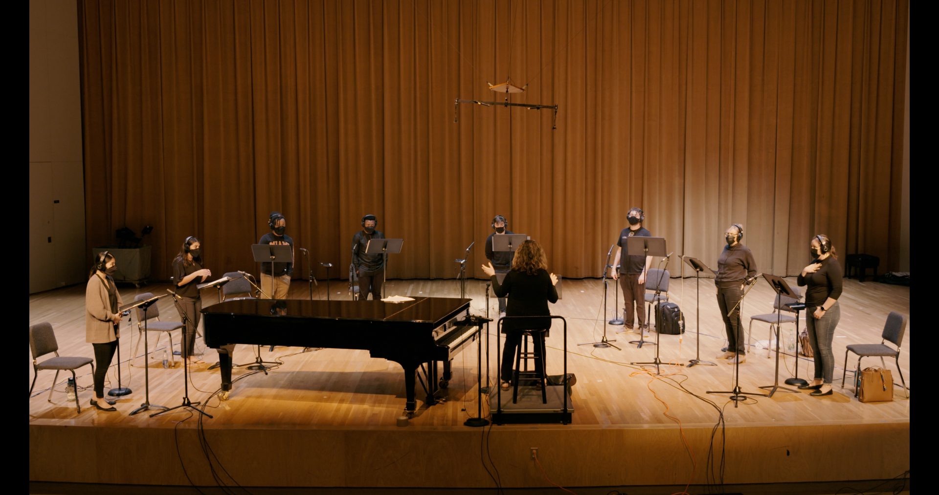 A choir recording their parts on stage.