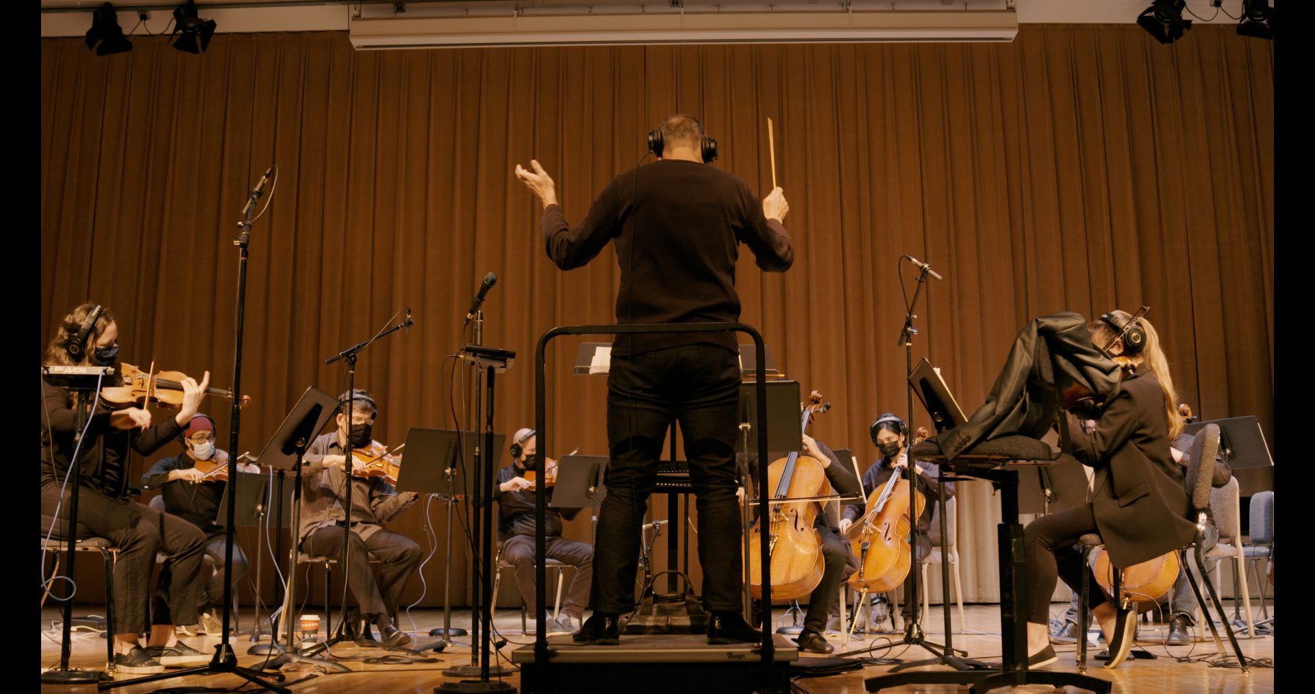 A conductor in front of a group of string instrumentalists.