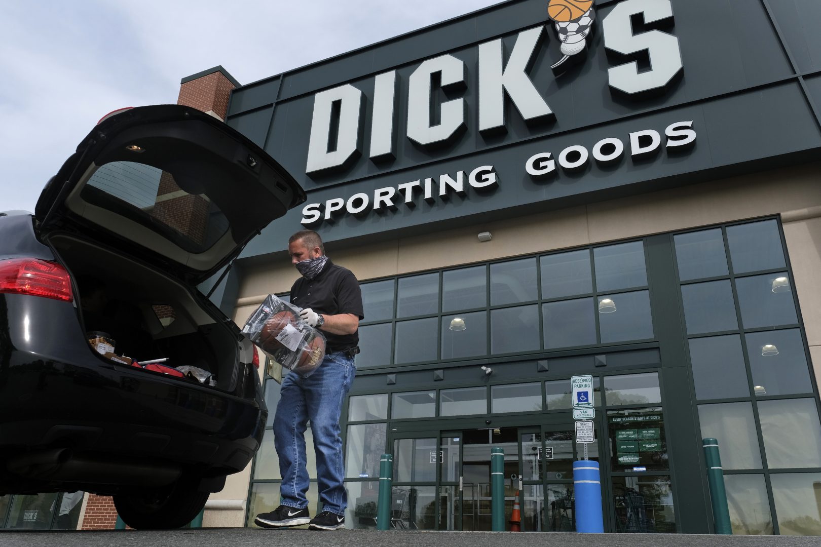 In this May 18, 2020 file photo, Gus Promollo delivers an order into a customer's trunk at Dick's Sporting Goods in Paramus, N.J.   A return to team sports is giving Dick’s Sporting Goods a lift in its first quarter as sales more than doubled. The company also raised its full-year outlook, Wednesday, May 26, 2021.  