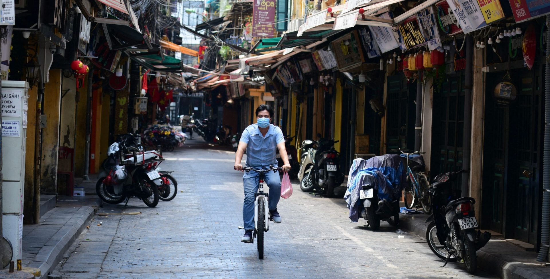 A man rides a bicycle on an empty street amid lockdown restrictions due to a surge in Covid-19 coronavirus cases in Hanoi on May 10, 2021.