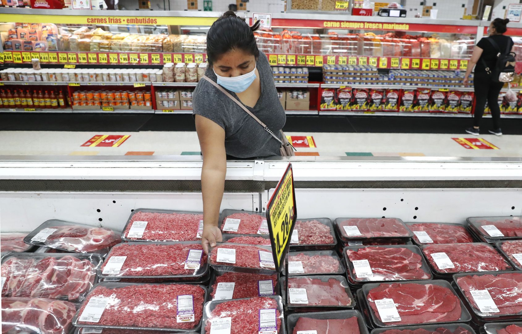 In this April 29, 2020 file photo, a shopper wears a mask as she looks over meat products at a grocery store in Dallas.   