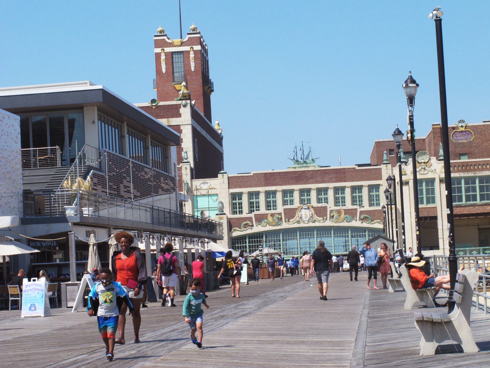A woman walks with two children on the boardwalk in Asbury Park N.J. on Friday, May 21, 2021. Businesses and residents alike expect this summer at the Jersey Shore to be busier than last year as more people get vaccinated and COVID19 restrictions are scaled back or eliminated.