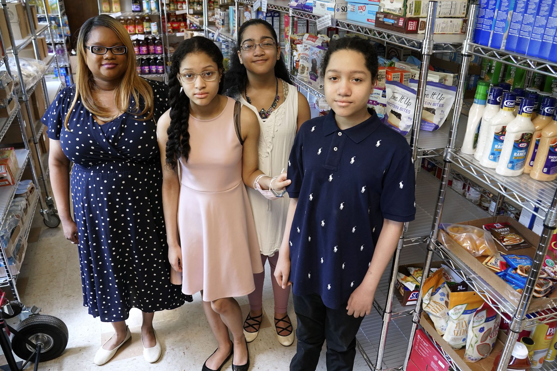 Aja Purnell-Mitchell, left, stands with her three children, Kyla, 13; Kyra, 15, and Cartier, 14, right, at a local food hub in Durham, N.C., on Friday, May 28, 2021, where they often help their mother. The teenagers have been learning remotely since last March but now plan to attend summer school after being vaccinated.