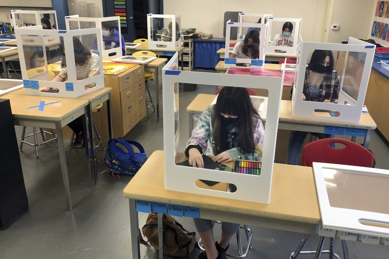 FILE PHOTO: In this March 2, 2021, file photo, socially distanced, and with protective partitions, students work on an art project during class at the Sinaloa Middle School in Novato, Calif.