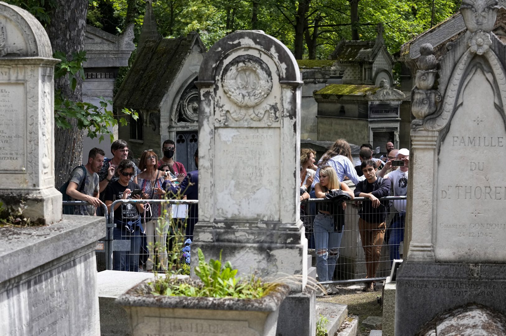 Fans gather at the tomb of rock singer Jim Morrison at the Pere-Lachaise cemetery in Paris, Saturday, July 3, 2021. (AP Photo/Michel Euler)