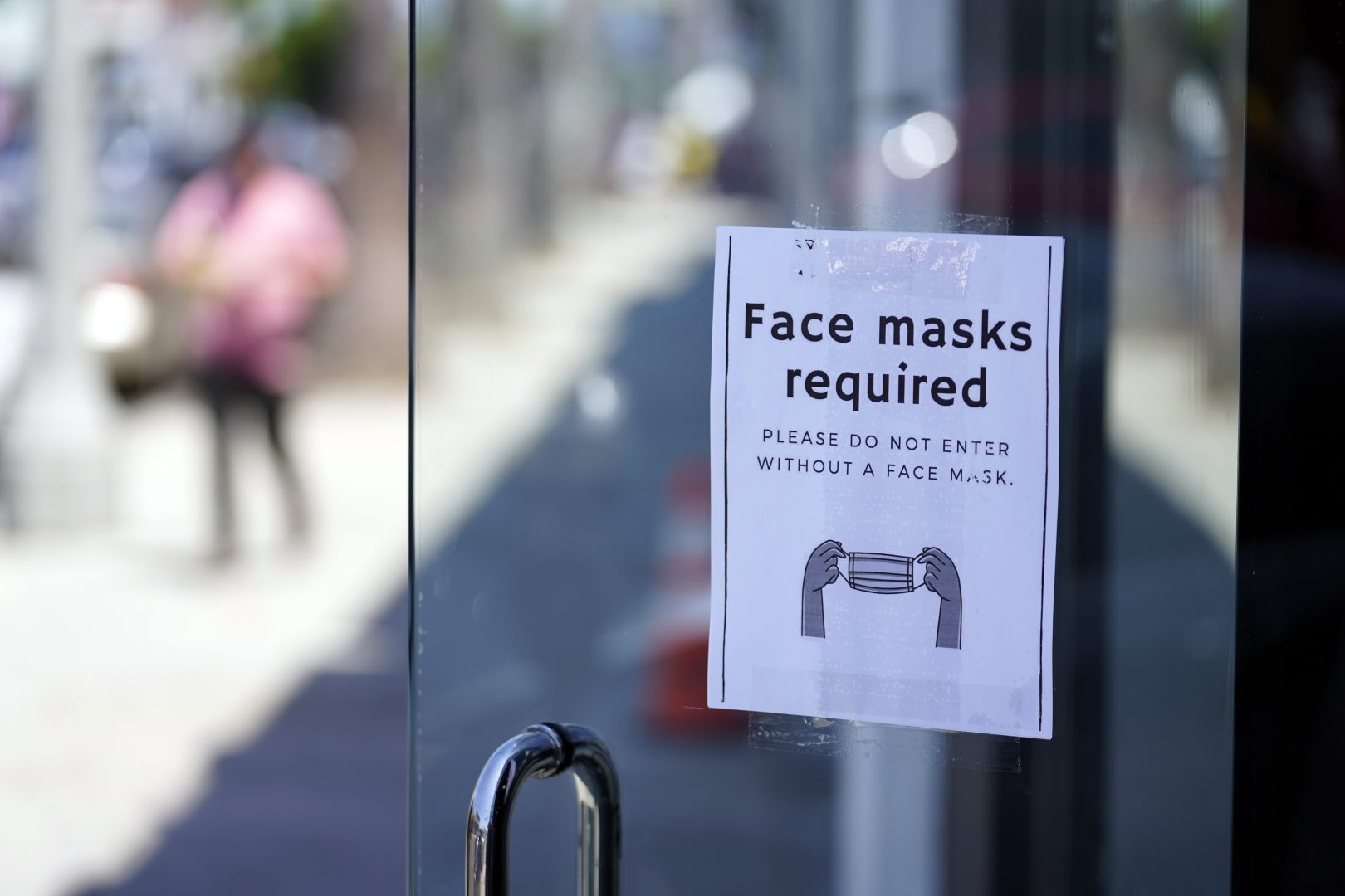 A sign advises shoppers to wear masks outside of a story Monday, July 19, 2021, in the Fairfax district of Los Angeles. 