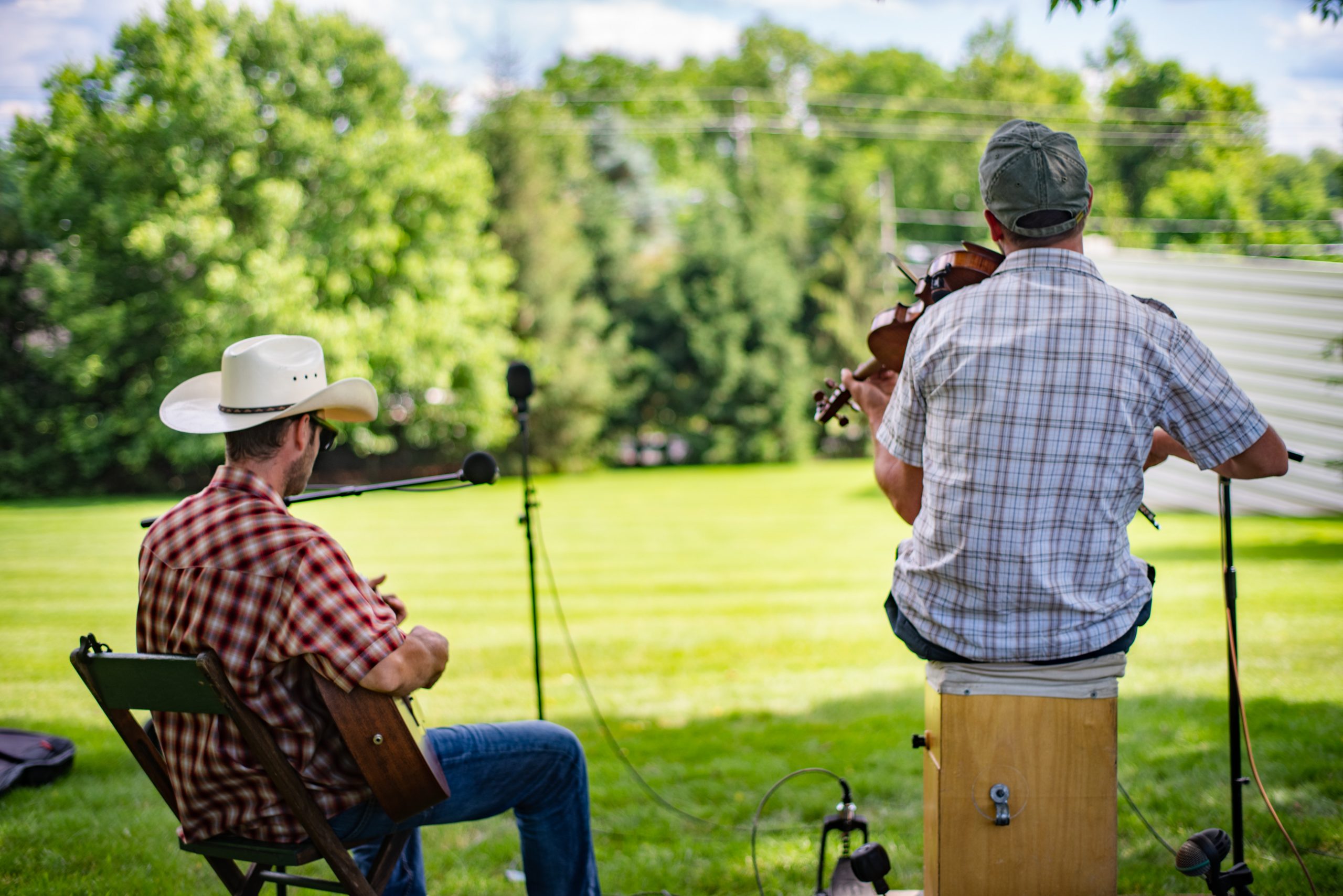 A shot from behind of George and Ian playing in front of a grassy lawn.