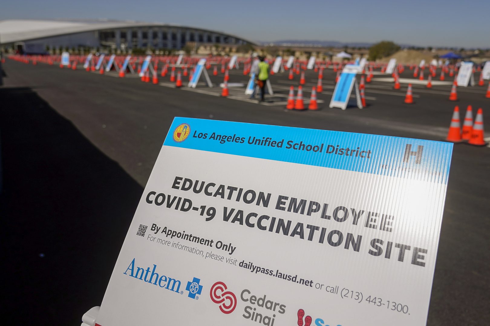 FILE PHOTO: In this March 2, 2021, file photo, a sign is displayed at a COVID-19 vaccination site for employees of the Los Angeles school district in the parking lot of SOFI Stadium in Inglewood, Calif. California will become the first state in the nation to require all teachers and school staff to get vaccinated or undergo weekly COVID-19 testing.