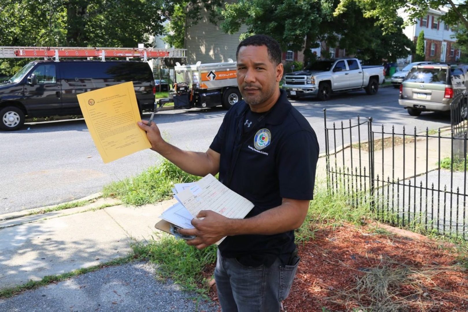 Allentown Housing Inspector Modesto Medina shows an example of the certificate property owners receive when their building passes inspection. At this location in the city's southern neighborhoods, Medina noted a discarded car wheel and other debris amid high weeds and grass, but the owner did not show up for the scheduled inspection.