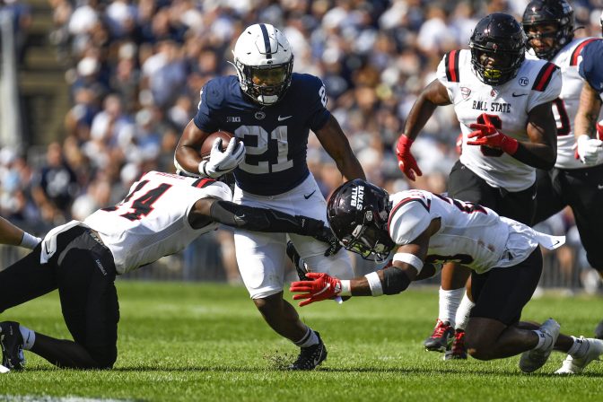 Penn State running back Noah Cain (21) splits two Ball State defenders on a first half run during an NCAA college football game in State College, Pa., on Saturday, Sept. 11, 2021. Penn State defeated Ball State 44-13.