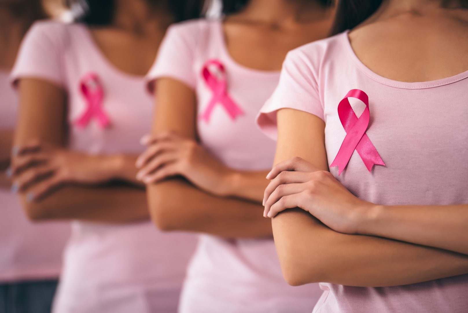 Group of young multiracial woman with pink ribbons in support of breast cancer awareness.