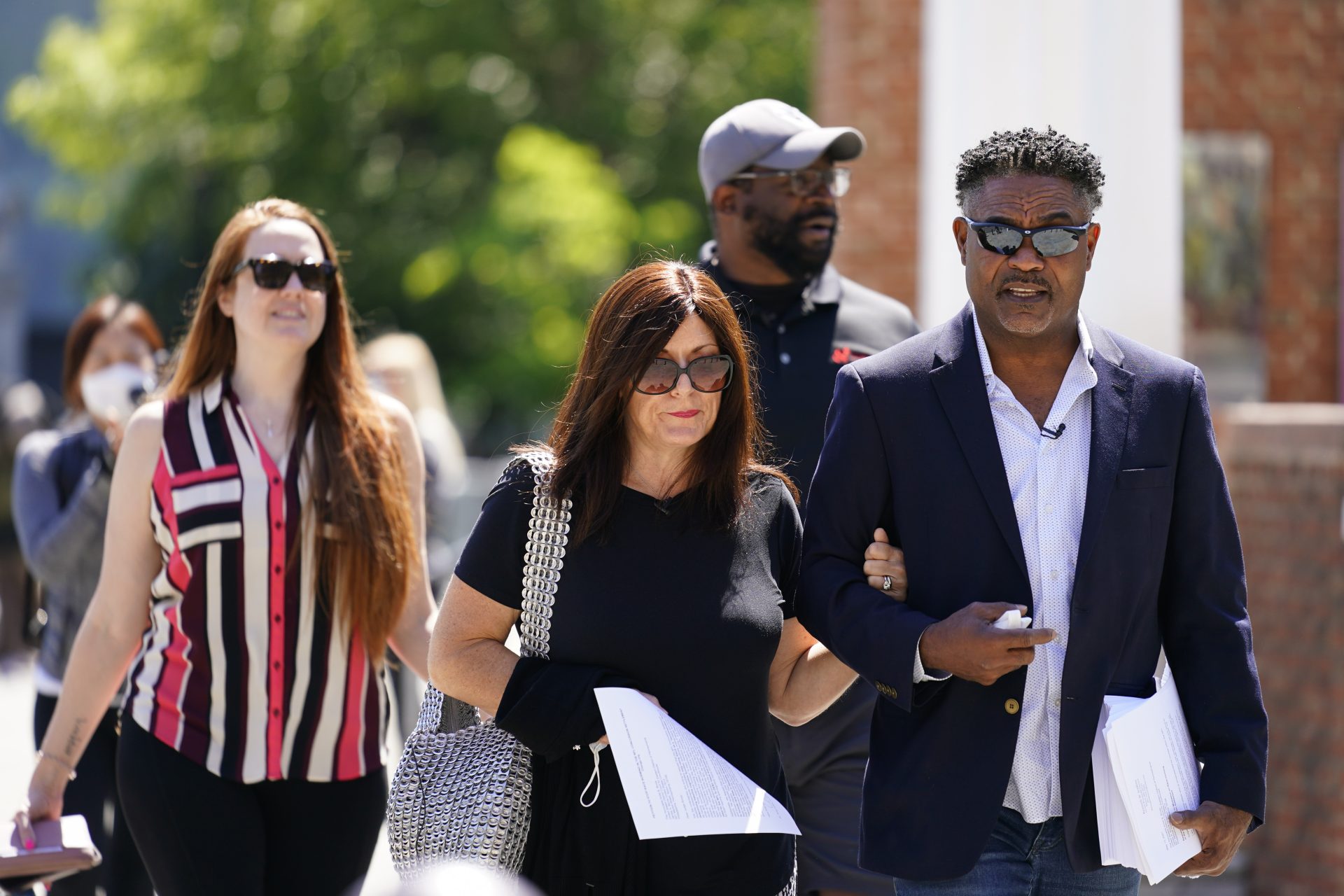 In this May 14, 2021, file photo, former NFL players Ken Jenkins, right, and Clarence Vaughn III, center right, along with their wives, Amy Lewis, center, and Brooke Vaughn, left, carry petitions demanding equal treatment for everyone involved in the settlement of concussion claims against the NFL, to the federal courthouse in Philadelphia