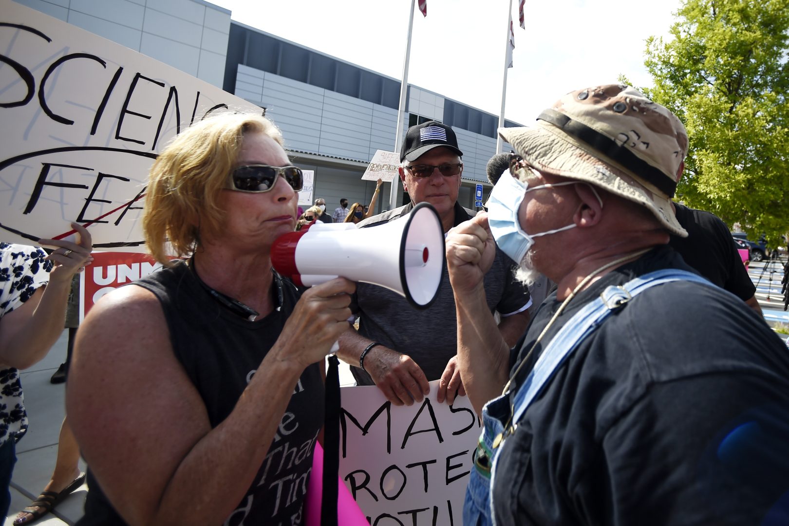 A pro-mask demonstrator, right, speaks with a non-mask demonstrator, left at the Cobb County School Board Headquarters during a pro mask wearing protest, Thursday, Aug. 12, 2021, in Marietta, Ga. Many school districts nationwide have seen parents protesting for and against masks.