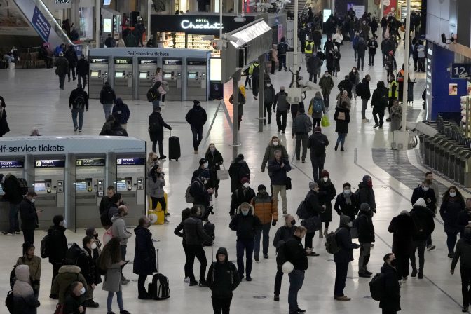 People pass through Waterloo train station, in London, during the morning rush hour, Monday, Nov. 29, 2021.