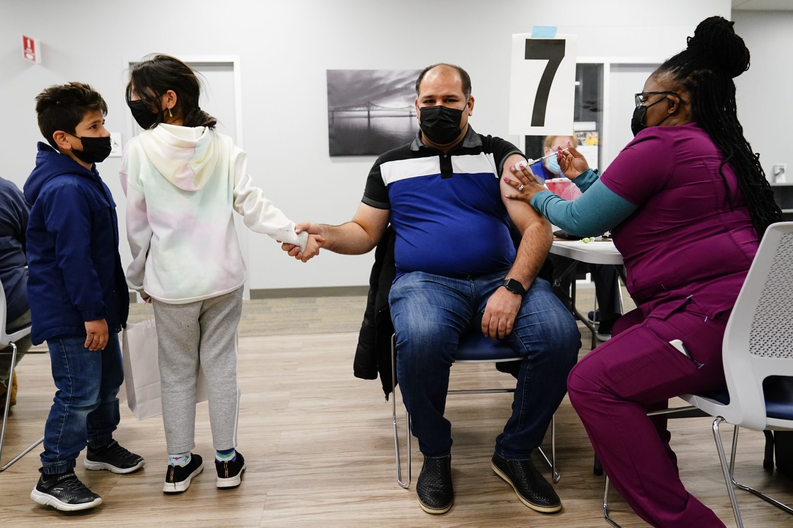 Nurse Sheena Davis, right, administers a dose of a Moderna COVID-19 vaccine to, Imran Amjad, as he holds his daughter's Falah Imran's hand and her brother Muhammad Ali Amjad, 6, looks on during a vaccination clinic at the Keystone First Wellness Center in Chester, Pa., Wednesday, Dec. 15, 2021. (AP Photo/Matt Rourke)