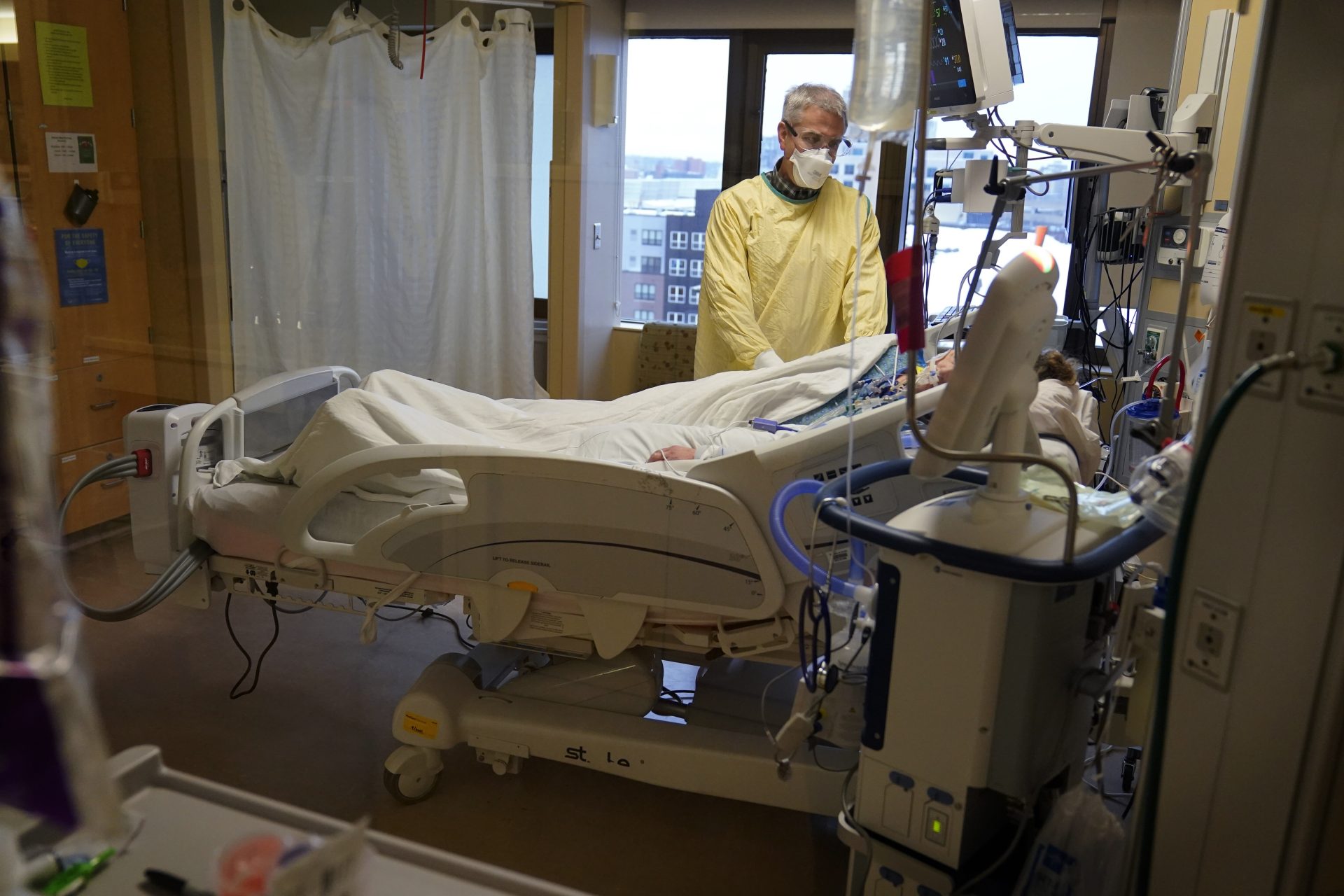 Steve Grove, a chaplain at Hennepin County Medical Center, prays in a COVID-19 patient's room, Friday, Dec. 10, 2021, in Minneapolis.