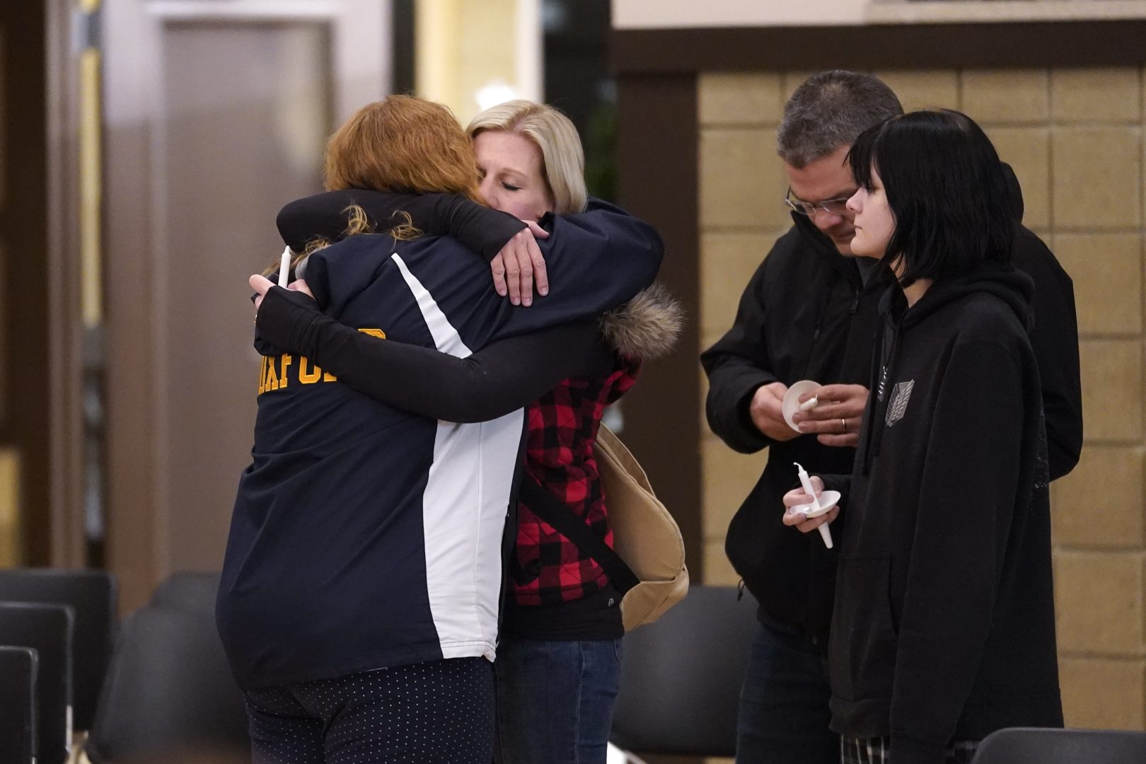 People attending a vigil embrace at LakePoint Community Church in Oxford, Mich., Tuesday, Nov. 30, 2021. Authorities say a 15-year-old sophomore opened fire at Oxford High School, killing three students and wounding several others, including a teacher. 