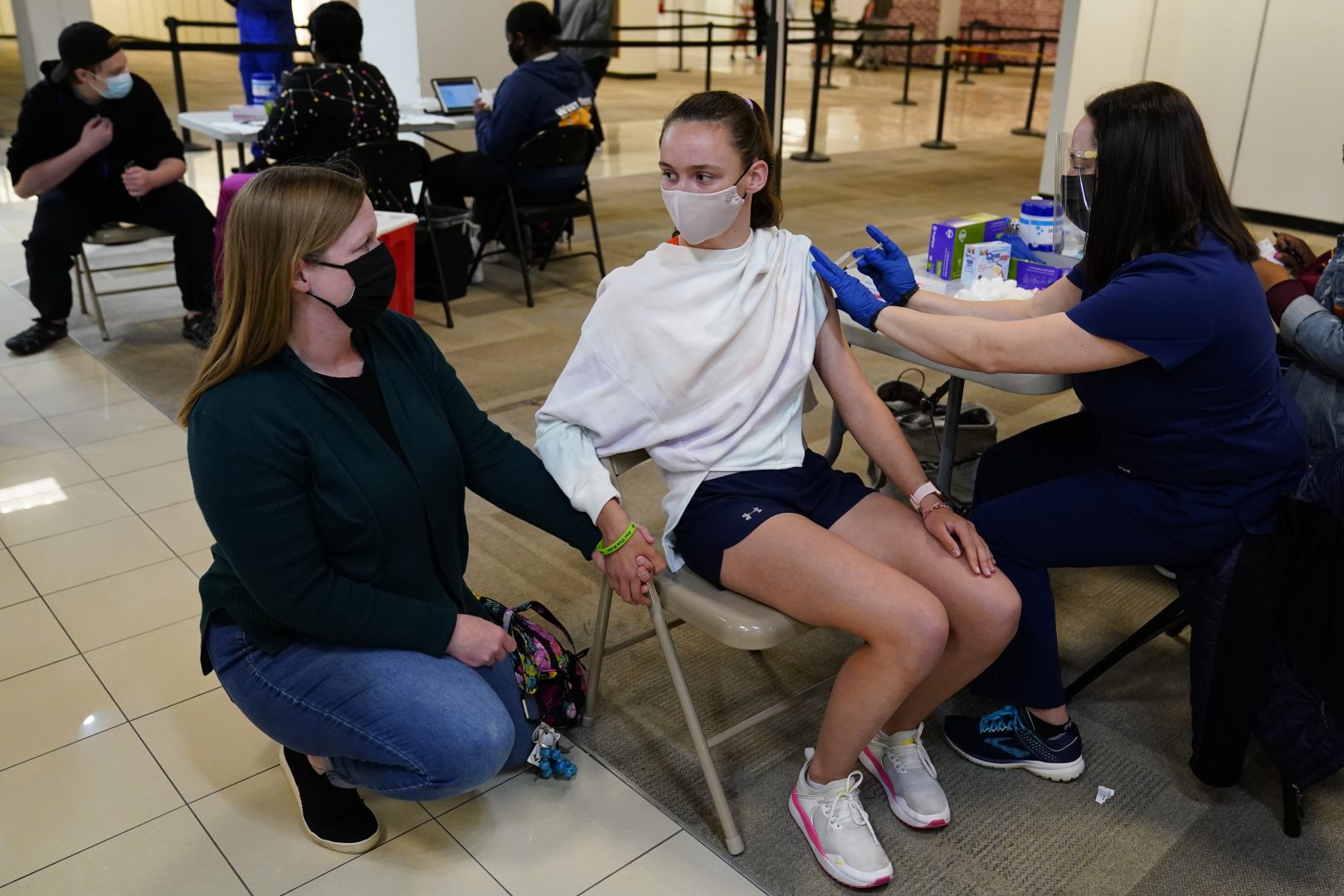 Meg Edwards, left, of Flourtown, Pa., comforts her daughter, Kate Edwards, 15, as she receives a Pfizer COVID-19 vaccination from registered nurse Philene Moore at a Montgomery County, Pa. Office of Public Health vaccination clinic at the King of Prussia Mall, Tuesday, May 11, 2021, in King of Prussia, Pa. 