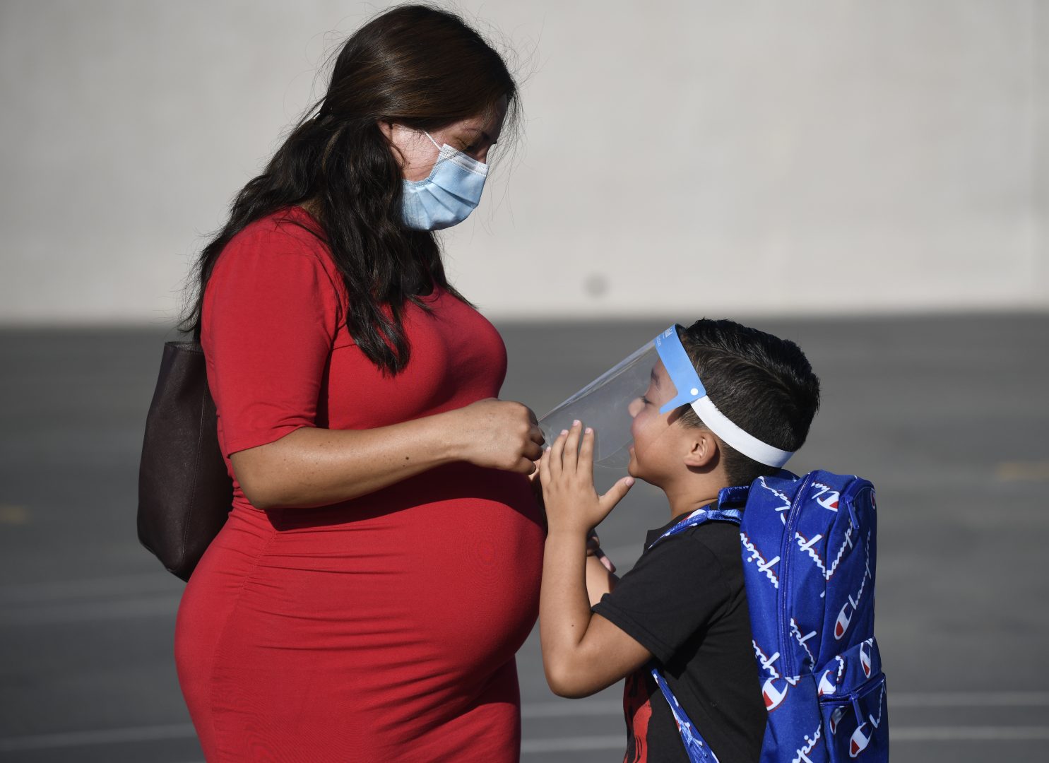 FILE - In this July 21, 2021, file photo, a parent adjusts her son's visor on the first day of school at Enrique S. Camarena Elementary School in Chula Vista, Calif. Parents in California on Friday, Oc.t 1, 2021, had mixed reactions to Gov. Gavin Newsom's plan to mandate coronavirus vaccinations for schoolchildren once they're fully approved by the FDA. Some welcomed the move as a way to keep children safe and classrooms open for learning and to try to put the pandemic behind. Others blasted the decision as premature, noting there is still no vaccine approved for the youngest children and questioning whether it's necessary. (AP Photo/Denis Poroy, File)