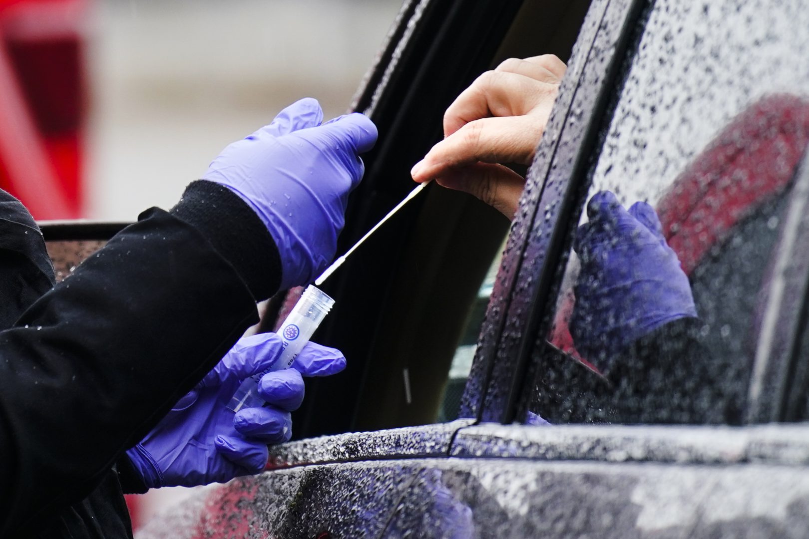 FILE - A driver places a swab into a vial at a free drive-thru COVID-19 testing site in the parking lot of the Mercy Fitzgerald Hospital in Darby, Pa., Thursday, Jan. 20, 2022. A requirement to get vaccinated against COVID-19 kicks in Thursday, Jan. 27,  for millions of health care workers in about half the states. (AP Photo/Matt Rourke, File)