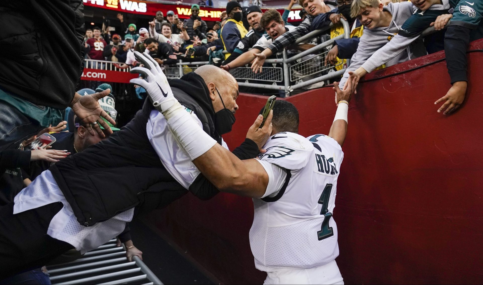 Fans falls onto Philadelphia Eagles quarterback Jalen Hurts (1) as the railing collapsed following the end of an NFL football game, Sunday, Jan. 2, 2022, in Landover, Md. Philadelphia won 20-16.