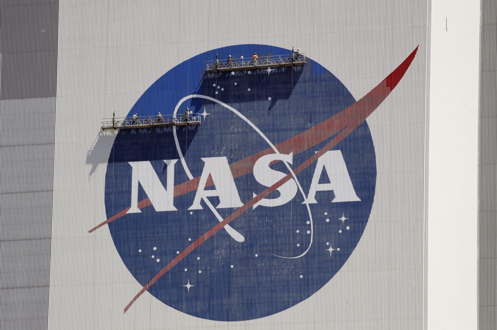 Workers near the top of the 526 ft. Vehicle Assembly Building at the Kennedy Space Center spruce up the NASA logo standing on scaffolds in Cape Canaveral, Fla., Wednesday, May 20, 2020. 