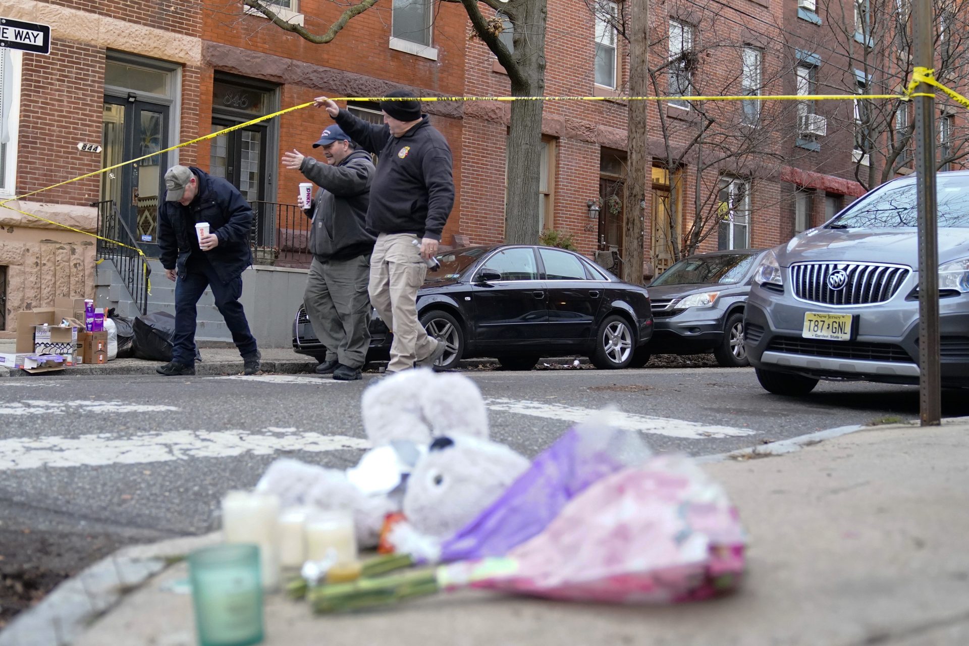 Officials pass flowers and other items left in memory of victims of Wednesday's fatal fire in the Fairmount neighborhood of Philadelphia on Thursday, Jan. 6, 2022. Officials say it's the city's deadliest single fire in at least a century.