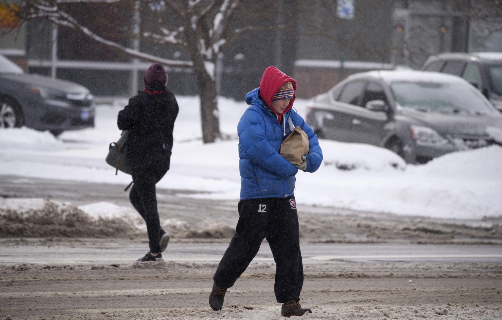 Bundled up against the cold, a pedestrian cradles a package while crossing in the intersection of Logan Street and Alameda as a winter storm sweeps over the intermountain West Wednesday Feb. 2, 2022, in Denver. Forecasters predict that the storm will move out Wednesday on to the eastern plains and on to the Midwest, which is bracing for heavy snowfall and icy conditions in the days ahead. (AP Photo/David Zalubowski)
