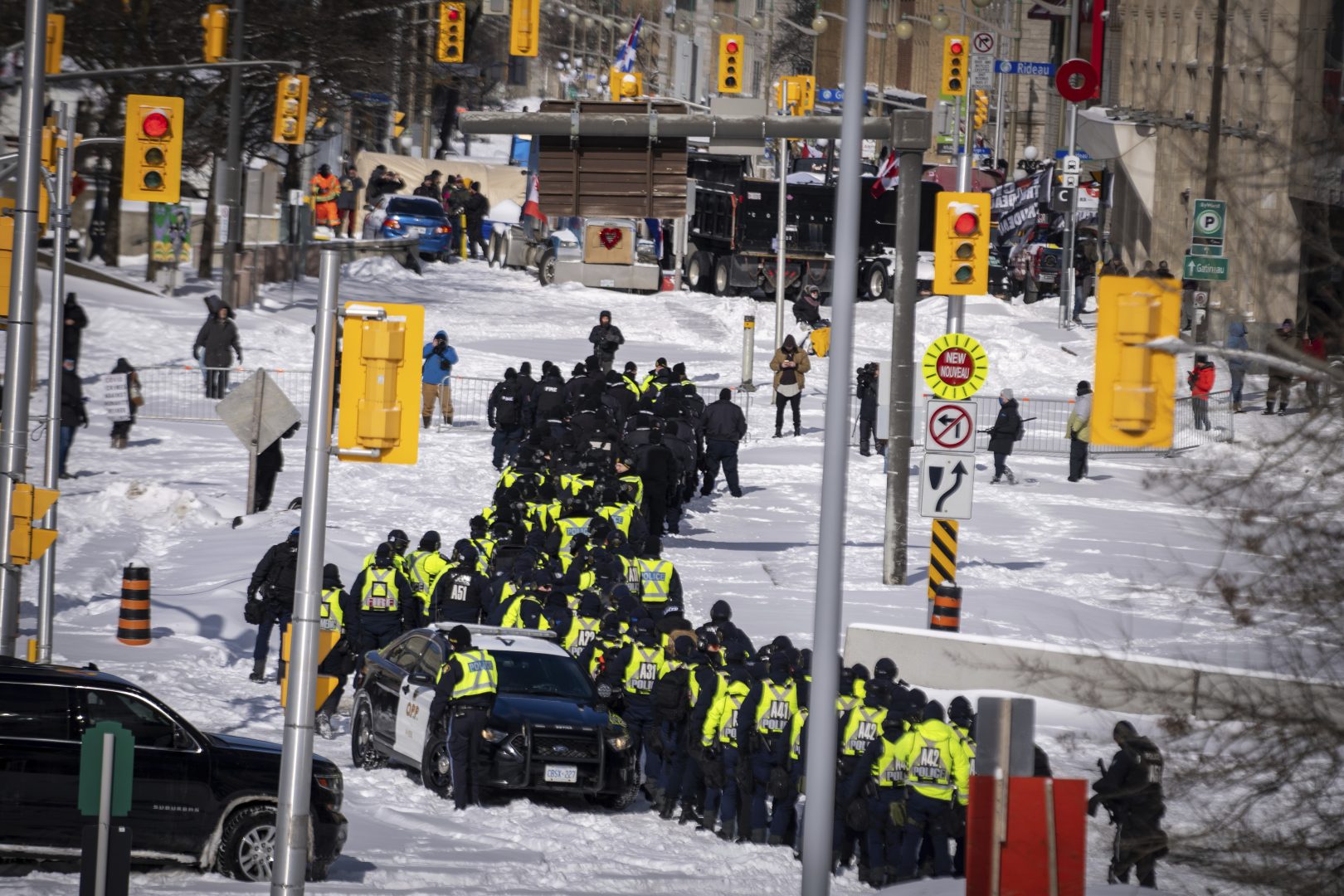 Police officers gather near the site of a trucker blockade in Ottawa, Friday, Feb. 18, 2022. Police began arresting protesters and towing away trucks Friday in a bid to break the three-week, traffic-snarling siege of Canada's capital by hundreds of truckers angry over the country's COVID-19 restrictions.  (AP Photo/Robert Bumsted)